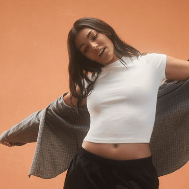 Woman in white crop top and gray cardigan.